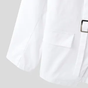 Primo piano della tasca del blazer bianco e dettaglio della fibbia quadrata in metallo