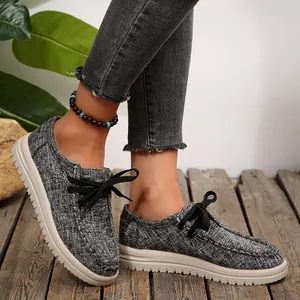 Detailopname van veterschoenen van canvas voor dames met dikke witte zolen op hout