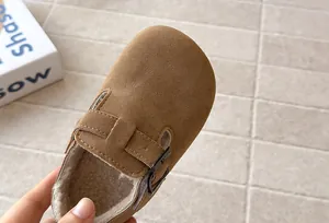Macro view of children's brown suede-like fleece-lined shoe featuring a metal buckle