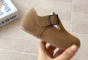 Detailed view of brown suede children's T-strap fur-lined shoe with metal buckle