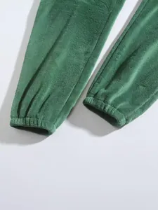 Detailopname van groene fleece joggingbroek met elastische manchetten en zachte textuur