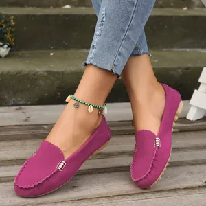 Primer plano de mocasines de ante magenta en una modelo sobre una terraza de madera