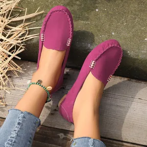 Vista detallada de mocasines de ante magenta con detalles metálicos decorativos y costuras