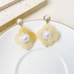 Vue détaillée de boucles d'oreilles fleurs en perles vintage sur une assiette blanche