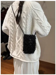 Detail view of a black fuzzy plush crossbody phone bag for autumn and winter.