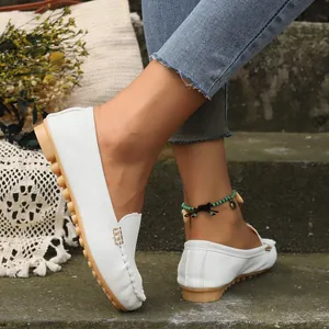 Vista detallada de cómodos mocasines blancos para mujer en los pies de la modelo