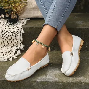 Detalle de cerca de mocasines blancos para mujer con hebilla de metal dorada