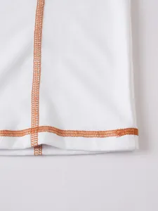 Détail en gros plan des coutures contrastées orange sur un tee-shirt Henley blanc