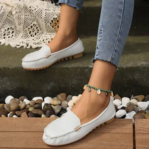 Primer plano de elegantes mocasines blancos para mujer presentados en rústicos escalones de piedra