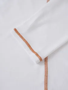 Détail en gros plan d'une manche de chemise Henley blanche avec surpiqûres orange