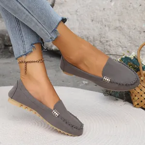Primer plano de mocasines de gamuza gris con hebillas metálicas y suelas de goma suave.