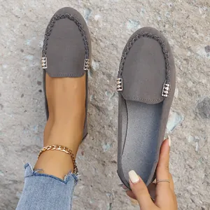 Detalle de mocasines de mezclilla gris con detalles metálicos y diseño sin cordones.