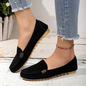 Detalle de mocasines de ante negro con hebilla dorada decorativa en los pies de una modelo