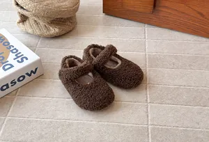 Primer plano de zapatos Mary Jane marrones de felpa para niñas en suelo beige