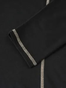 Gros plan sur les coutures contrastées crème au poignet d'un chemisier Henley noir pour hommes.