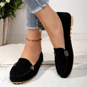 Primer plano detallado de mocasines de gamuza negra con hebillas doradas usados por modelo.