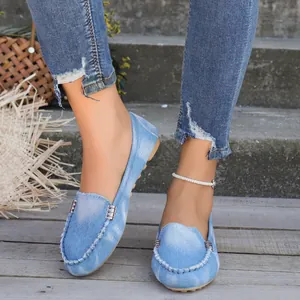 Primer plano de mocasines de mezclilla azul claro con hebillas metálicas y detalles cosidos a mano