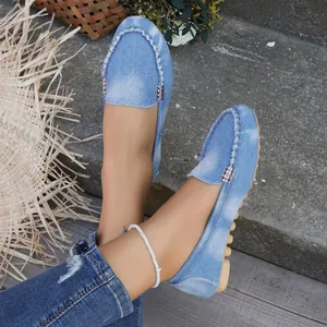 Primer plano de mocasines de mezclilla azul claro para mujer con hebillas de metal finas.