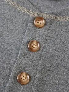 Gros plan de trois boutons marrons sur un t-shirt Henley gris décontracté avec texture tricot.