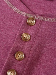 Détail de quatre boutons marbrés marron sur l'encolure d'un t-shirt Henley en maille