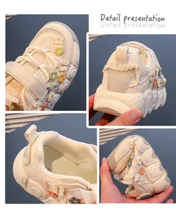 Detailed view showing the texture, floral embroidery, and flexibility of the girls' white sneakers.