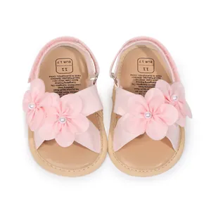 Dettaglio di fiori in tessuto rosa con perle su sandali da principessa per neonata