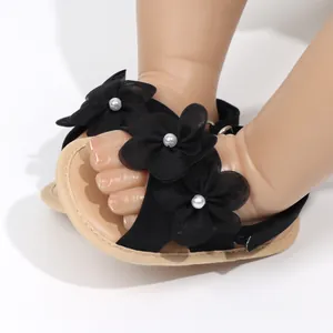 Dettaglio di sandali neri da principessa per neonata con fiori e perle