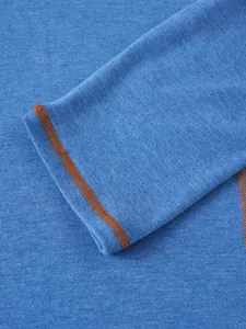 Détail rapproché du poignet d'un t-shirt Henley bleu à manches longues, couture orange