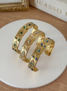 Macro detail view of hammered gold evil eye cuff bracelets with colorful crystal inlay