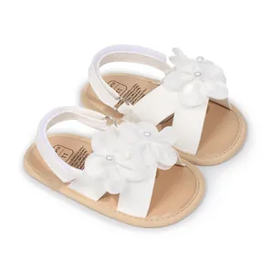 Dettaglio di sandali da principessa per neonata bianchi con eleganti fiori in tessuto
