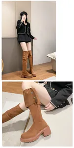 Nahaufnahme brauner Overknee-Stiefel aus Wildleder mit modischen Schnallendetails.