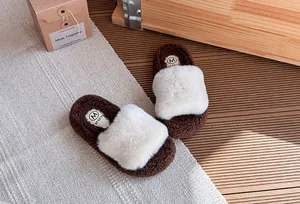 Vista dettagliata delle ciabatte di peluche marrone e bianco per bambine con suole spesse