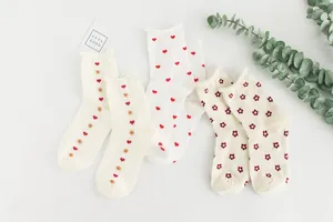 Detailed view of three pairs of white cotton socks with cute heart and flower patterns