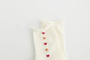 Detailed view of cream mid-calf socks featuring cute red heart and flower pattern embroidery