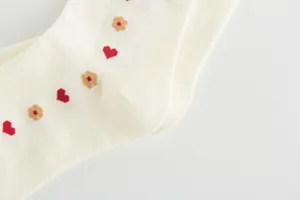 Detail shot of cream mid-calf cotton socks with cute red heart pattern embroidery
