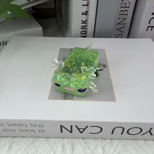 Jouet squishy axolotl vert pailleté pour le stress posé sur la surface d'un livre