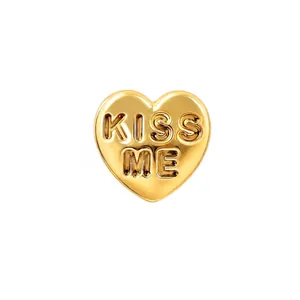 Macro detail of a 18k gold-plated titanium heart stud featuring KISS ME embossed text