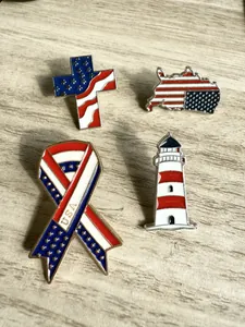 Détail de quatre pin's émaillés drapeau USA en forme de croix, carte, ruban et phare.