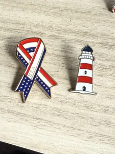 Détail des épinglettes en forme de ruban avec drapeau américain et phare sur bois.
