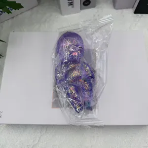 Détail d'un jouet squishy bébé violet à paillettes dans un emballage plastique.