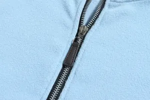 Gedetailleerde macro-opname van de metalen rits op het lichtblauwe polarfleece sweatshirt