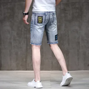Detailed back view of men's slim denim shorts with embroidered patch and frayed hem.