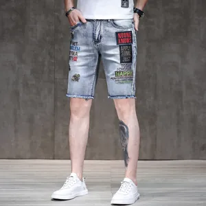Detailed view of men's slim fit light blue denim shorts with bee embroidery and raw hem