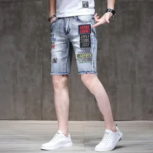 Close-up of stylish slim-fit denim shorts with colorful embroidered patches and frayed hems