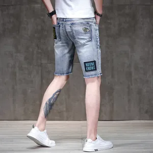 Slim fit blue denim shorts for men featuring bee embroidery and raw frayed hem detail