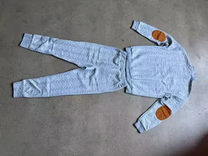 Detalle del conjunto de sudadera y pantalón gris con textura y parches en los codos