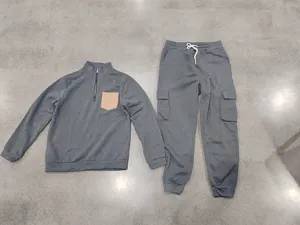 Flat lay view of a grey heavy fleece tracksuit set featuring a quarter-zip pullover