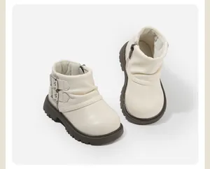 Detailansicht von cremefarbenen Mädchen-Stiefeletten mit seitlichen Schnallen und Reißverschluss.