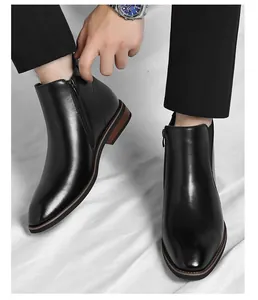Close-up detail of men's black leather Chelsea boots with functional side zipper closure.