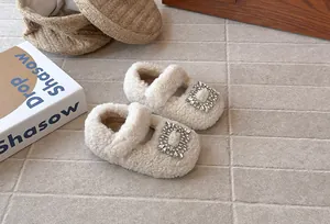 Detailaufnahme weißer Plüsch-Babyschuhe mit funkelnder Strass-Viereck-Schnalle